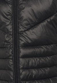 Czarna puchowa kamizelka o gładkiej, błyszczącej fakturze z pikowanym przeszyciem, zamkiem błyskawicznym na środku oraz dopasowanym krojem.
