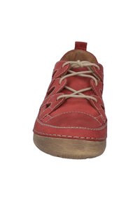 Red leather sports shoe with lace-up design, cut-out details, beige laces, and a textured brown rubber sole.