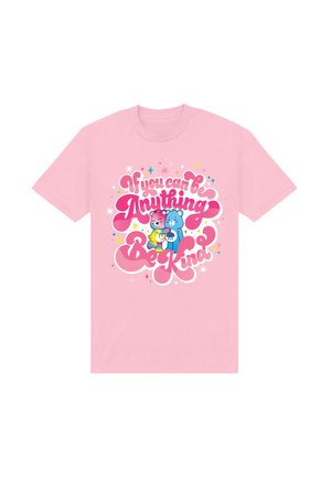 Roze T-shirt met kleurrijke knuffelberen en de boodschap "Als je alles kunt zijn, wees dan vriendelijk" omringd door sterren en fonkelingen.