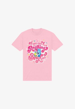 Roze T-shirt met kleurrijke knuffelberen en de boodschap "Als je alles kunt zijn, wees dan vriendelijk" omringd door sterren en fonkelingen.