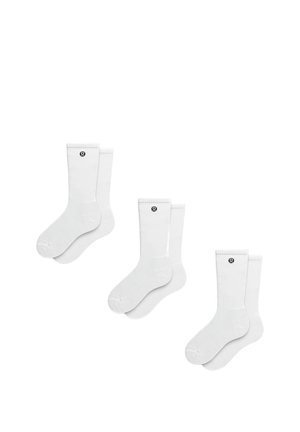 Chaussettes blanches en coton pour homme avec bords côtelés et logo noir sur le côté, présentées par lot de trois paires. Texture douce et forme standard.