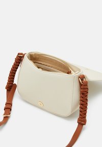 Kermavaale värvi käekott, millel on pebbeldatud tekstuur, pruuni punutud rihmaga ja kuldse magnetklambri ning tõmblukuga sisetaskud.