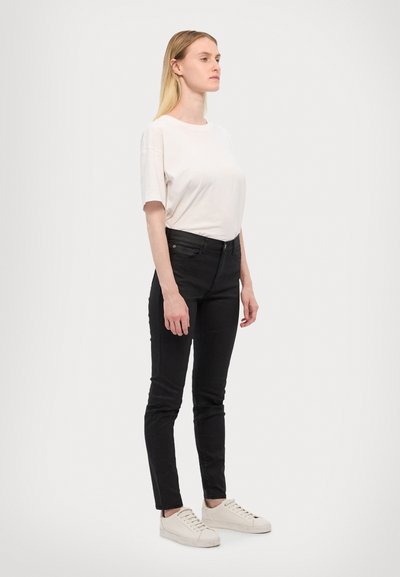 Hvit kortermet t-skjorte kombinert med svarte skinny jeans og hvite sneakers. Minimalistisk design, glatt stoff med avslappet passform.
