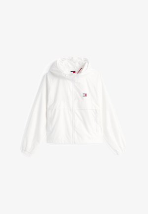 Balta sukapota striukė, pagaminta iš lengvos medžiagos, su priekiniais užtrauktukais, elastiniais rankogaliais ir maža logotipu ant krūtinės. Dvi priekinės kišenės.