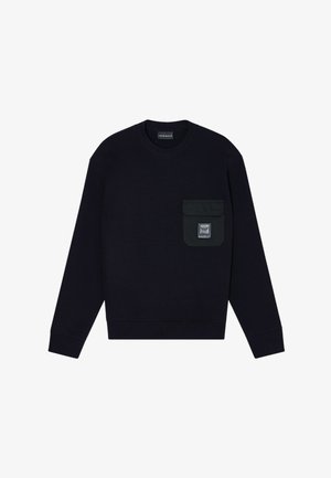 Sweat-shirt noir à manches longues avec col rond et une poche rabat sur la poitrine gauche, arborant un petit écusson en forme de rectangle.