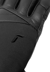 Guantes negros hechos de cuero y tela, con una textura suave, detalles cosidos y un logo en la zona de la muñeca.