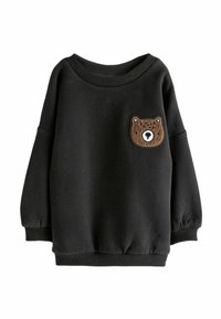 Sweatshirt noir avec un col rond, des épaules tombantes et une patch de ours brun sur la poitrine. Tissu doux avec des poignets côtelés.