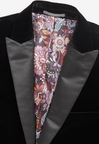 Blazer di velluto nero con rever in satin, dotato di una fodera interna con motivo in rossi scuri, rosa e verdi, che mostra disegni floreali.