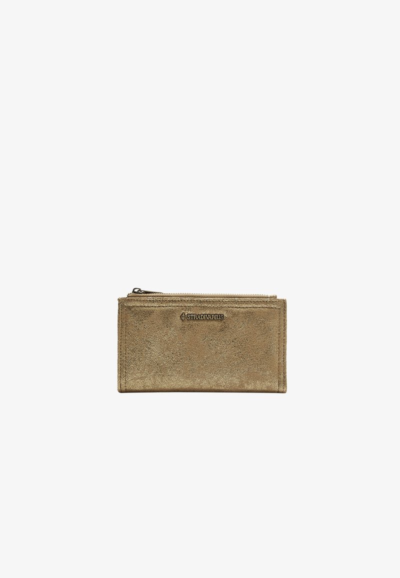 Portafoglio zip dorato metallico con una texture liscia, caratterizzato da un dettaglio del logo e una forma rettangolare. Design compatto ideale per carte e contante.