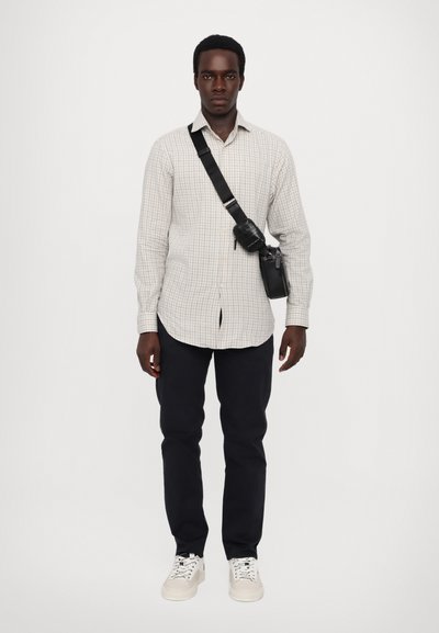Light gray checkered shirt, black crossbody bag, dark pants, and white sneakers. Casual fit, button-down design, and visible stitching details.