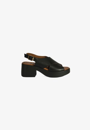 Schwarze Leder-Slingback-Sandale mit Blockabsatz, offener Zehenpartie und Ausstanzung. Mit einer beigen Innensohle und einem seitlichen Schnallenverschluss.