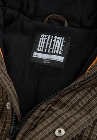 Czarne wnętrze kurtki z polaru z czarną metką z napisem "OFFLINE" i miejscem na imię, brązowa kratowana tkanina zewnętrzna oraz częściowo otwarty zamek błyskawiczny.