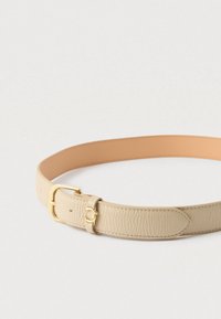 Μπεζ δερμάτινη ζώνη με υφή, διαθέτει χρυσή αγκράφα και λείο ταμπά κάτω μέρος. Ρυθμίζεται με τρύπες για το μέγεθος.