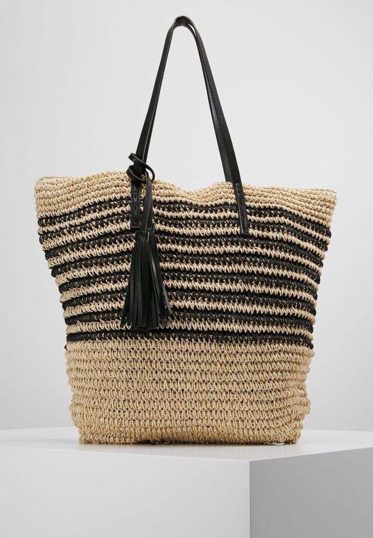 Tkaná slamá taška s černými a přírodními pruhy. Obsahuje dvě černé kožené uši a dekoraci v podobě třásně. Prostorný design.