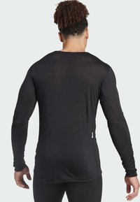 Czarna, długosleeve'owa koszulka sportowa, wykonana z lekkiego materiału, posiada okrągły dekolt, dopasowany krój oraz subtelne, teksturowane wykończenie.