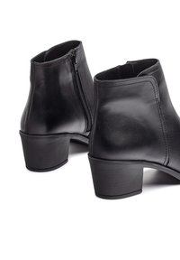 Botas de tobillo de cuero negro con una textura suave, tacón bajo y cremallera exterior para ponérselas con facilidad.
