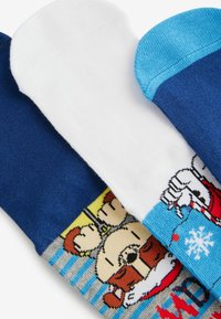 Tres pares de calcetines: azul oscuro, blanco y azul claro. El calcetín blanco presenta un diseño de caricatura. Material suave, de punto, con textura lisa.