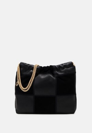 Zwarte patchwork schoudertas met zachte textuur en dubbele gouden kettingriem tegen een effen witte achtergrond.
