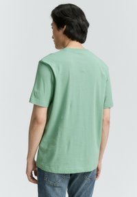 Camiseta de algodón de manga corta, color verde menta, con cuello redondo y un corte relajado, que presenta una textura suave y un diseño sencillo.