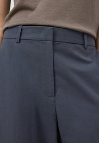 Marinblå byxor i slät tygkvalitet, med en platt midja, sidofickor och en minimalistisk design med diskreta söms detaljer.