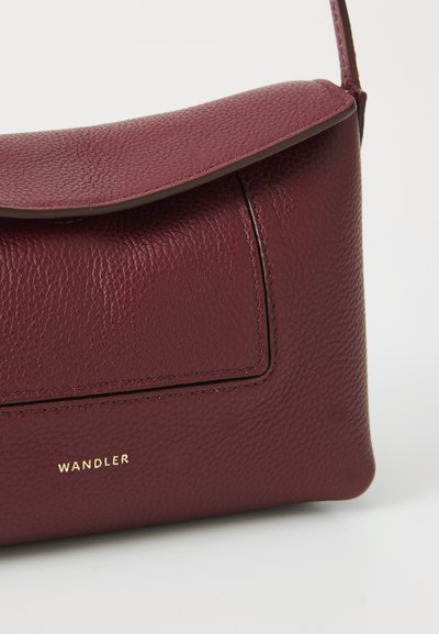 Mörkröd läderväska med texturerad yta, fälllock och frampocket. Har en guldfärgad "WANDLER"-logotyp i botten.