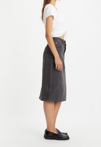 Grå denim midi kjol med rak skärning och framfickor, tillsammans med en vit kort topp och svarta loafers. Slät textur, avslappnad design.