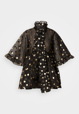 Svart gjennomsiktig kjole med gullfargede prikker, volangkrage og volanger på ermene. Har en utvidet silhuett og dekorative volanger nedover fronten.