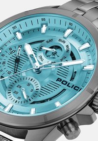 Policijos laikrodis su sidabriniu nerūdijančio plieno dirželiu, turkio spalvos ciferblatu, turinčiu kelis subciferblatus, ir baltais valandų žymekliais bei rodyklėmis.