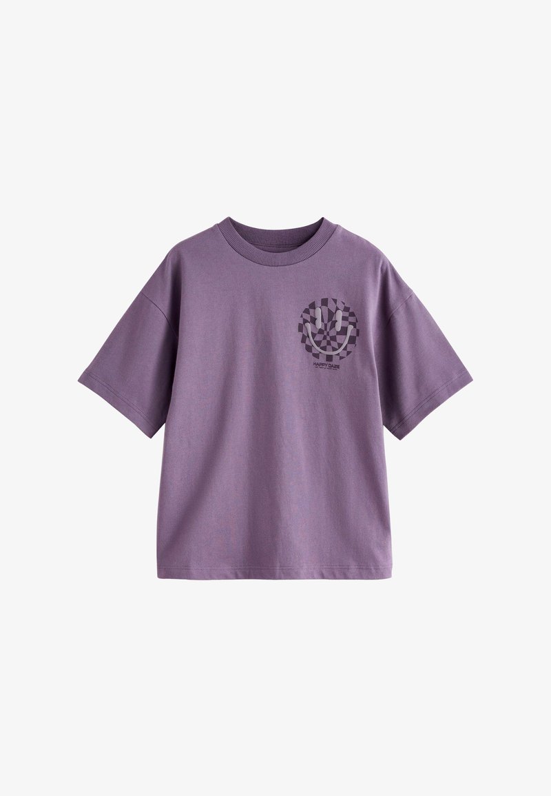 T-shirt oversize violet à manches courtes avec un visage smiley à damier noir et blanc et le texte « HAPPY DAZE » sur le côté gauche de la poitrine.