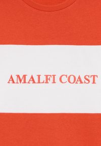 Piros pamut pulóver, fehér vízszintes csíkkal, amelyen vörösen hímzett "AMALFI COAST" felirat található. Klasszikus, kerek nyakkivágással.