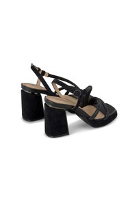 Czarne zamszowe sandały na obcasie z kwadratowym noskiem, szerokim blokowym obcasem i krzyżującymi się paskami z metalicznym akcentem dla dodatkowej tekstury.