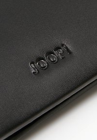 Černá kožená peněženka s embosovaným logem "JOOP!". Hladká textura s elegantním designem a minimalistickým vzhledem.