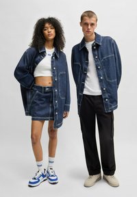 Denim jasje en rok set, blauwe denim, lichte wassing, met knopen, gecombineerd met witte tops en casual sneakers met blauwe accenten.