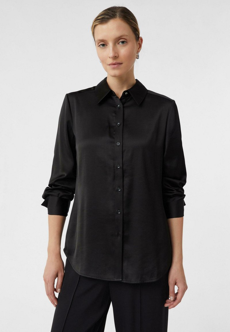 Black satin button-up shirt with a collar, long sleeves, and rolled cuffs. Smooth texture and a curved hemline. Subtle sheen.