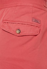 Tessuto robusto color corallo con trama visibile e tasca a pattina con dettaglio bottone ed etichetta cucita.