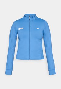 Blå zip-up langærmet træningsjakke med høj krave, ellesse-logo på venstre bryst og lille emblem på højre bryst.