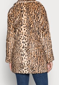 Abrigo de estampado animal con un patrón en beige y negro, textura suave y diseño holgado. El abrigo tiene un corte de longitud media y mangas anchas.