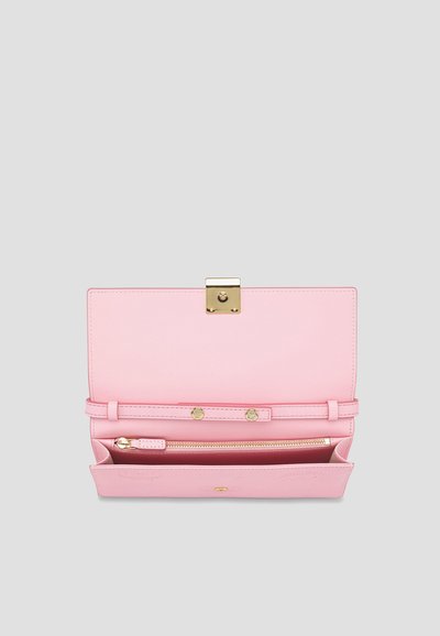 Ροζ δερμάτινο πορτοφόλι ανοιχτό που δείχνει ένα χρυσό κούμπωμα, λουράκι με κουμπί και εσωτερικό διαμέρισμα με φερμουάρ σε γκρι φόντο.