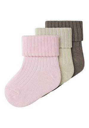 Trzy pary prążkowanych skarpetek dla niemowląt z wywiniętymi mankietami w kolorach różowym, kremowym i brązowym, ułożone w stos na białym tle.