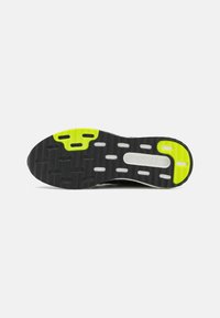 Suela de zapato de goma negra con acentos en verde y blanco. Presenta un patrón texturizado y recortes para mejorar la tracción y la flexibilidad.