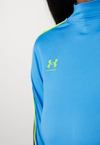 Blauses Sportshirt aus glattem, leichtem Gewebe. Mit hohem Kragen und neongrünen Akzenten an den Ärmeln. Unter Armour-LogoDisplayed.