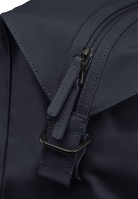 Sac à dos navy avec un tissu texturé, double fermeture éclair et un accent en métal noir. Les tirettes de fermeture éclair sont plates et de couleur assortie.