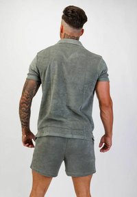 Grå, kortärmad polo skjorta och matchande shorts i mjukt, strukturerat tyg, som visar en bakvy med subtila sömnadsdetaljer.