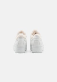 Weiße Ledersneaker mit einem kragen aus Fell. Flache weiße Gummisohle, dezentes Markenlogo an der Ferse und glatte Textur.