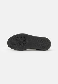 Sole in gomma nera con texture a nido d'ape e area liscia con logo. Forma sagomata per vestibilità e comfort.