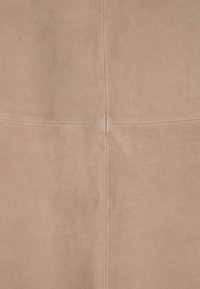 Helle beige semsket stoff med en jevn tekstur, som har diskrete sømmer og et minimalistisk design. Ingen pynt eller mønstre synlige.