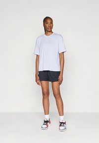 Világoskék rövid ujjú póló, fekete hálós rövidnadrággal párosítva. Fehér zokni, és fekete, piros, valamint fehér sportcipők teszik teljessé az atletikus megjelenést.