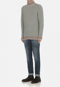 Grå stickad turtlenecktröja med ribbade bruna detaljer, tillsammans med mörkblå jeans med uppvikt fåll och svarta mocka chelsea boots.