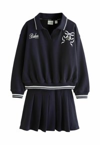 Conjunto azul marino de dos piezas que incluye un suéter con cuello, ribetes blancos y detalles bordados, combinado con una falda plisada. Textura de tela suave.