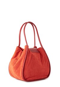 Bolso tote de pana rojo con acentos de cuero liso y asas alargadas; textura suave, forma redondeada y líneas verticales pronunciadas.